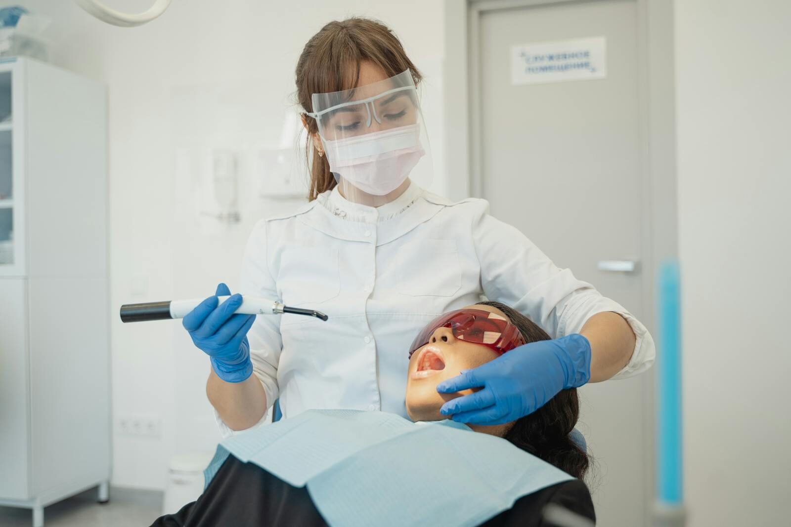 A female dentist using curing light on a patient in a modern dental clinic.